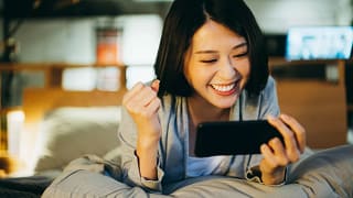 excited person lying on bed looking at phone screen.jpg