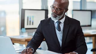 getty person in suit at desk laptop thoughtful thinking x cf.jpg