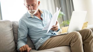 senior man couch docs calc laptop gettyimages .jpg