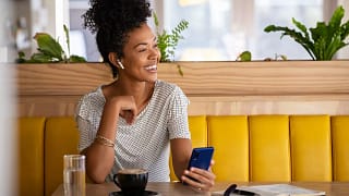 smiling person holding phone sitting in coffee shop.jpg