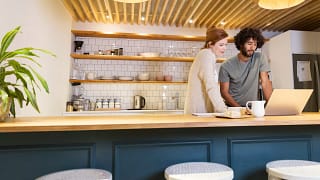 two people standing at kitchen counter looking at a computer.jpg