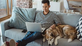 young man on laptop on couch with dog Lvpg.width .jpg
