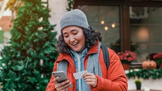 young woman outdoors smiling with phone and c.width zIAeLdf.jpg