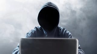 Hooded figure at laptop EBPOVYO.width .jpg