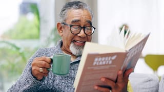 getty smiling happy reading book with mug.jpg