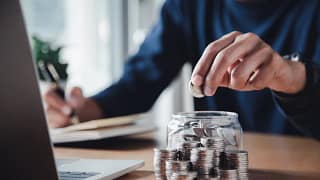 gettyimages saving coins in a jar writing in a journal.jpg