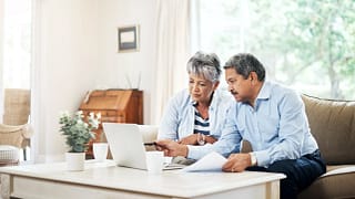 two older people sitting on a couch looking at a laptop copy.jpg