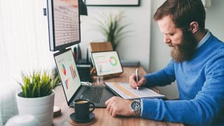 bearded person at desk by computer taking notes.jpg