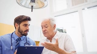 senior man talking to doctor holding clipboard medical expenses healthcare hospital.jpg