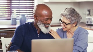 smiling mature couple using laptop at home.jpg