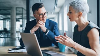 two businesspeople talking in front of a laptop.jpg