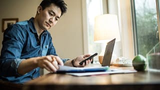 person in home office holding smartphone and looking at document.jpg