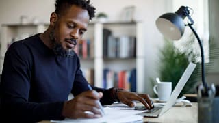person sitting at a desk looking at a laptop and documents.jpg