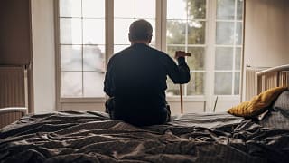 retired man with cane sitting on bed.jpg