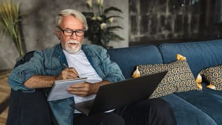 senior holding laptop and writing note in notebook.jpg