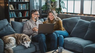 two older people sitting on a couch looking at a laptop.jpg