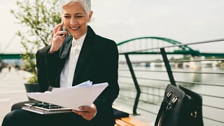 mature senior businesswoman woman on phone looking at documents.jpg