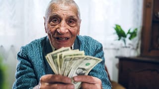 senior man counting cash money bills social security retire invest inflation cola getty.jpg