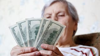elderly woman retirement social security holding one hundred dollar bills cash getty.jpg