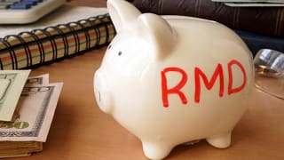 getty images piggy bank with rmd written on its side next to stack of paper money retirement savings k ira cash x bdf.jpg