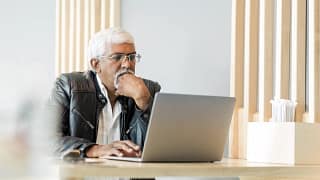 retired older man on laptop working reading news stocks.jpg