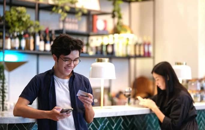 man in restaurant holding phone and credit ca.width UCoaDCF.jpg