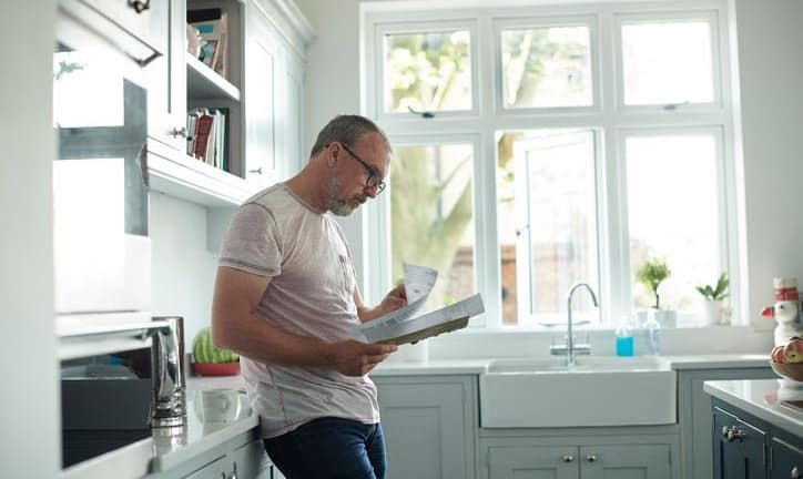 worried man in kitchen with bills fEoJV.width