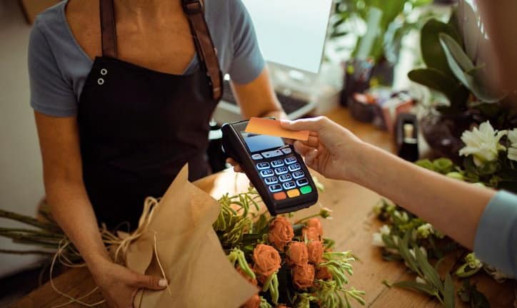 woman holding credit card over payment reader.width IAlpwc.jpg