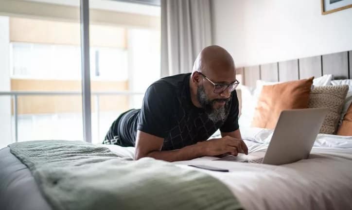 person lying on bed using laptop zxzVvg.width .jpg