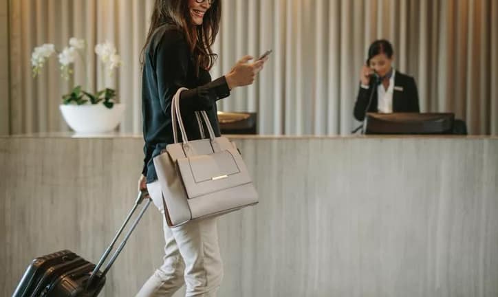 woman with suitcase and phone in hotel lobby.width .jpg