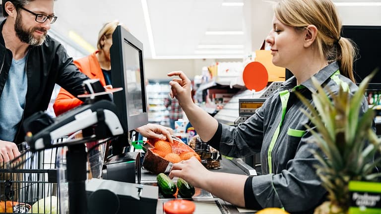 Grocery store employee ringing up customers .width