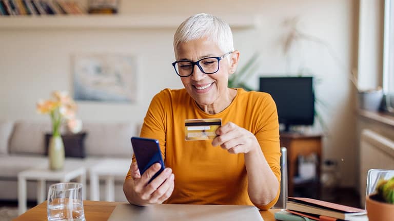 Mature woman smiling while holding credit car.width wrRdZh.jpg