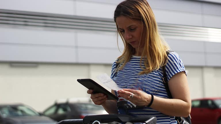 Woman in grocery store parking lot examining .width TGwgWbC