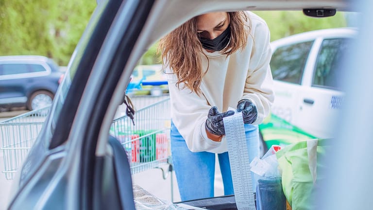 Woman loading car with groceries looks over h.width QbypC