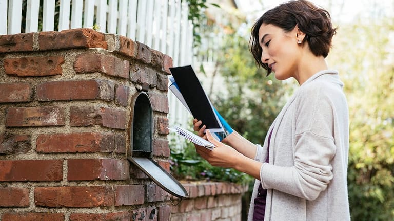 Woman sorting through mail at her mailbox mbL.width