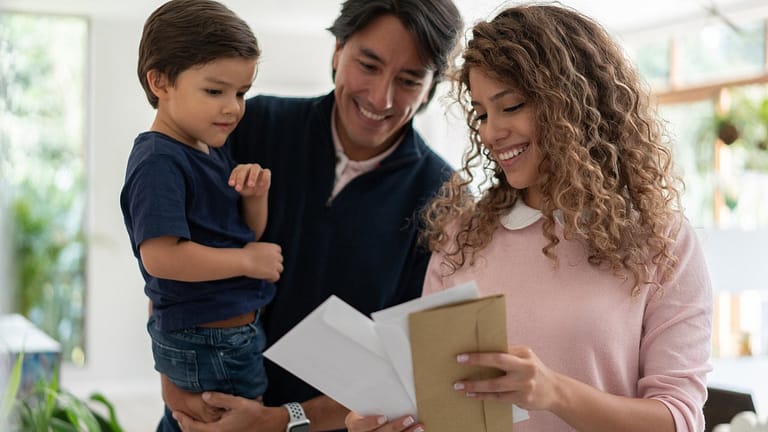 Young family smiles while looking through mai.width YCkchbc