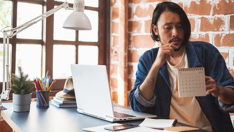 Young man pausing from using his laptop to lo.width GUCxw