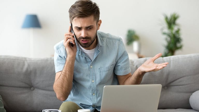 man on couch on phone call near laptop gfF.width .jpg