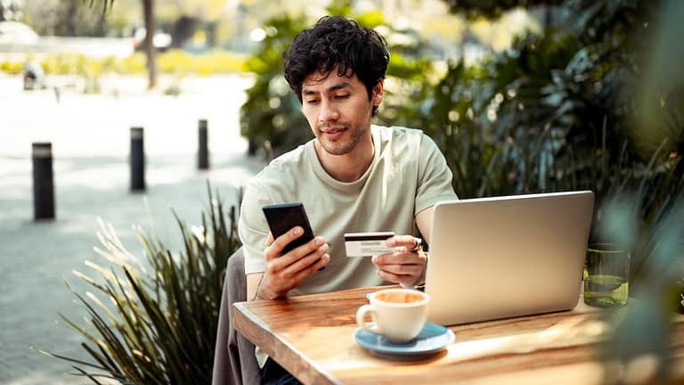 person at outdoor cafe table with laptop phon.width AODczLu.jpg