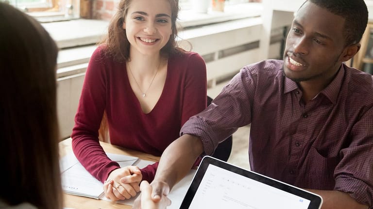 Couple shaking hands over paperwork at a desk.width jzUDgFs.jpg