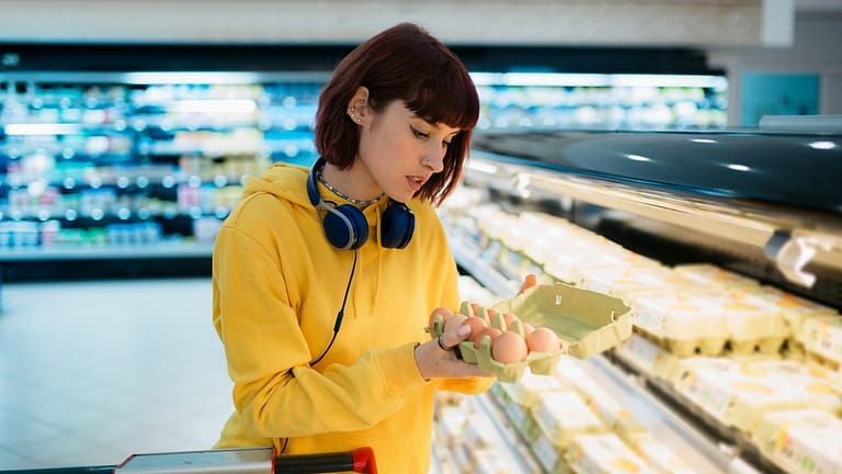 Shopper inspecting a carton of eggs in the gr.width .jpg