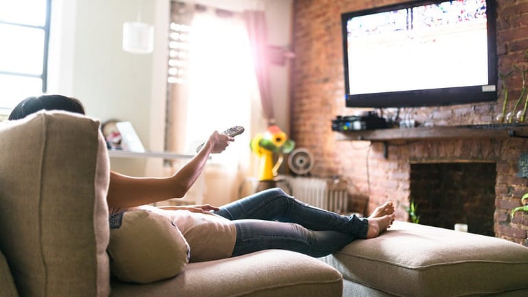 Woman lounging on her sofa watching tv hUjj.width .jpg