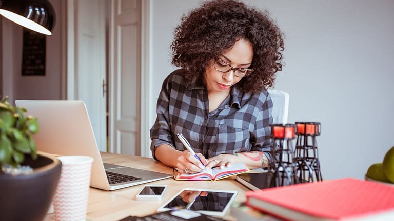 Woman taking notes while using a laptop IpOrU.width .jpg