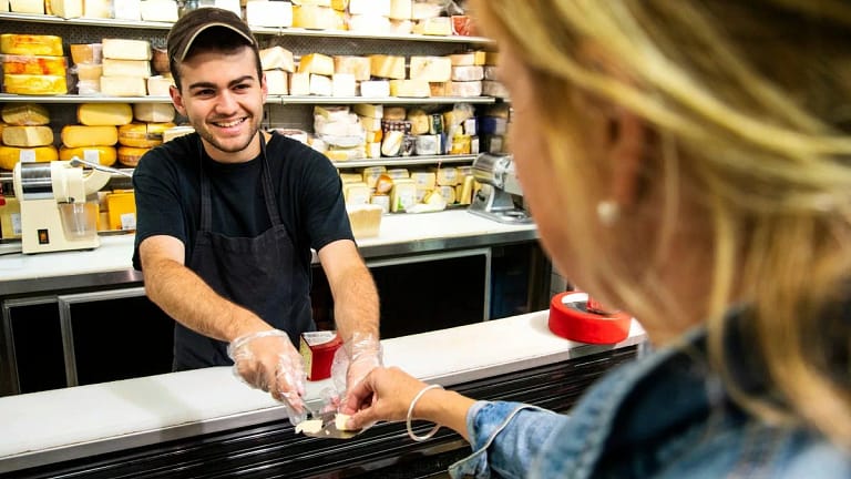 Employee handing sample of cheese to woman sh.width QAGKAOI.jpg