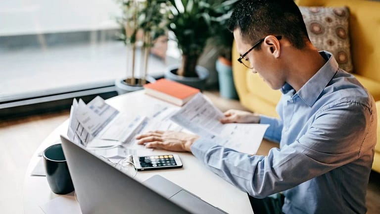 MAn using a calculator and looking over docum.width bFwUjX.jpg