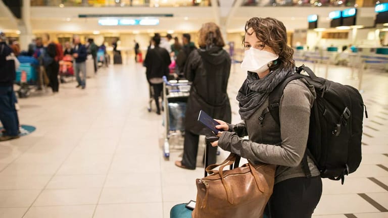 Masked woman with luggage waiting in an airpo.width ogAmB.jpg
