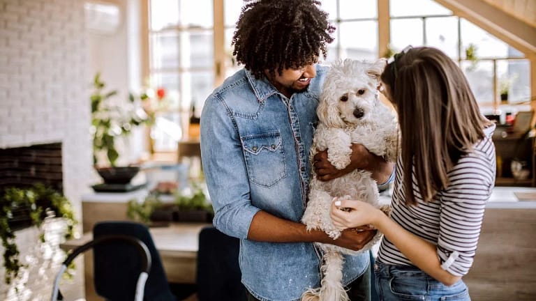 Millennial couple holding dog inside home io.width .jpg