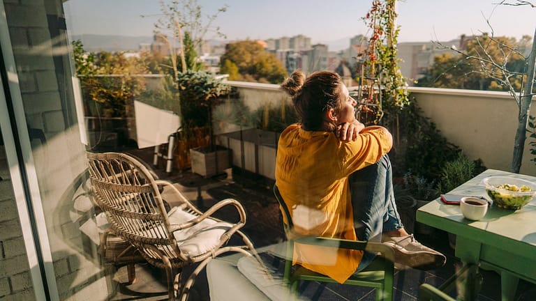 Woman sitting outside on her condo balcony Hq.width .jpg
