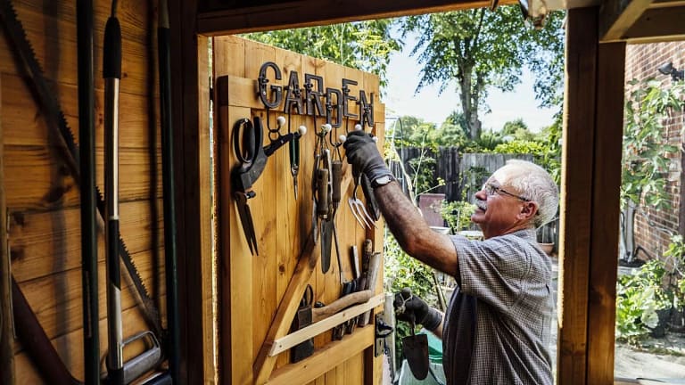 Homeowner storing gardening tools in his shed.width .jpg