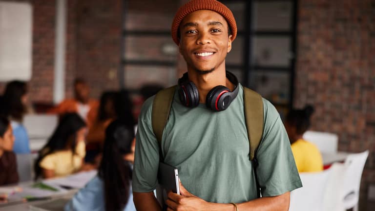 a person with a backpack and headphones around their neck holding a laptop gettyimages .jpg